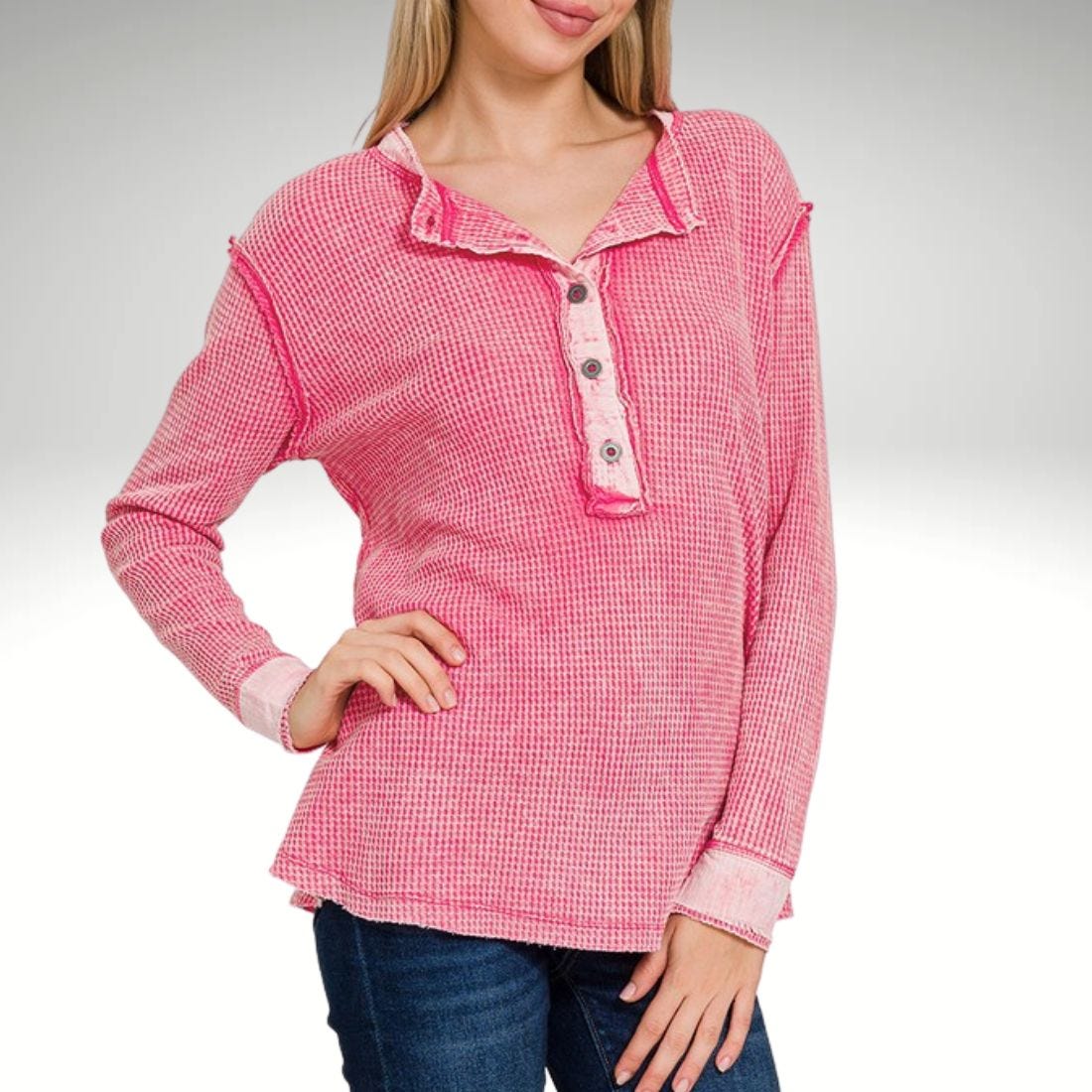 A woman is wearing a long-sleeve pink and white checkered henley shirt.
