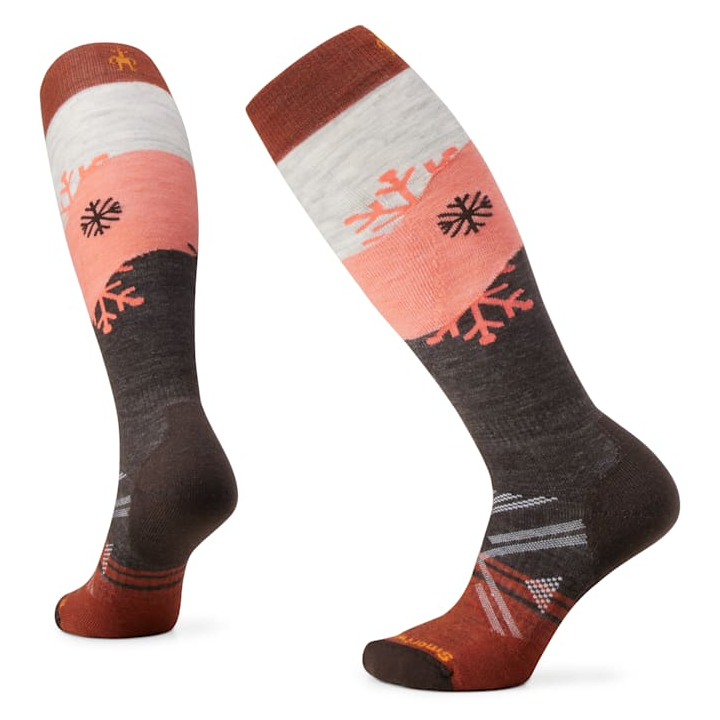 Knee-high socks with a design featuring snowflakes and color blocks in shades of brown, pink, and white. Made by Smartwool, they appear warm and suitable for colder weather.