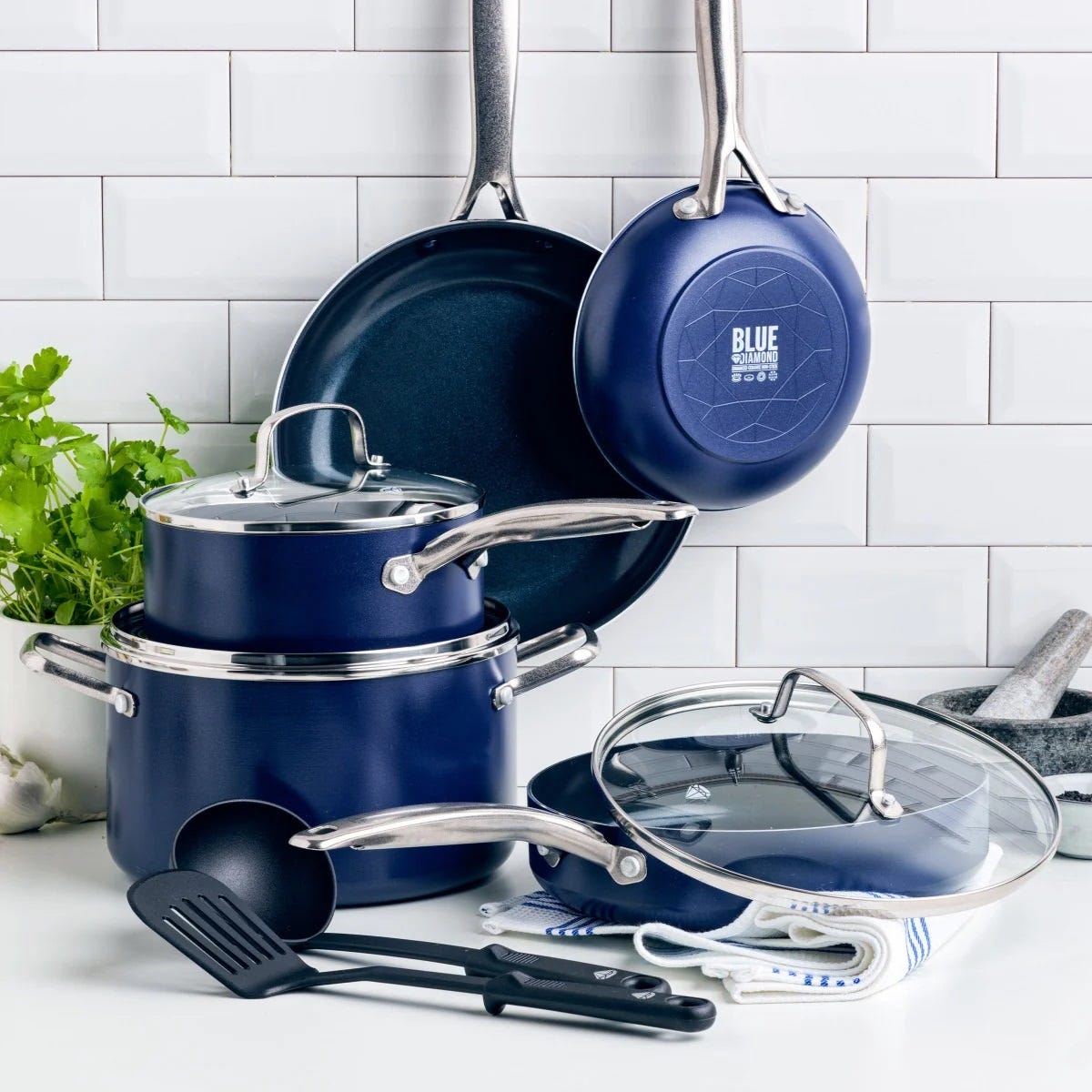 A set of blue cookware including pots, pans, lids, and kitchen utensils.