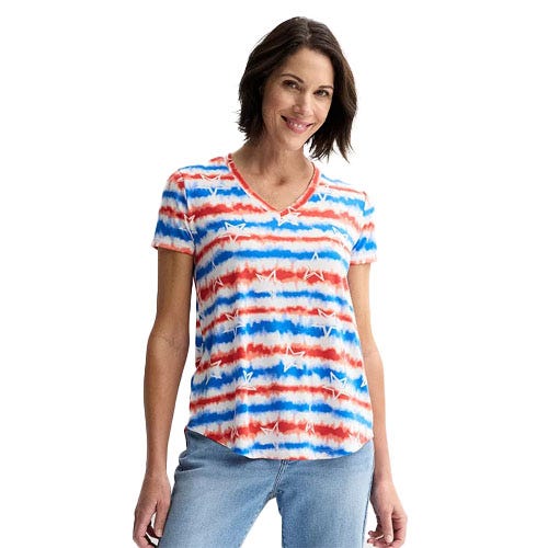 A woman is wearing a short-sleeve T-shirt with a red, white, and blue tie-dye pattern featuring stars. The shirt has a V-neck and is paired with light blue jeans.