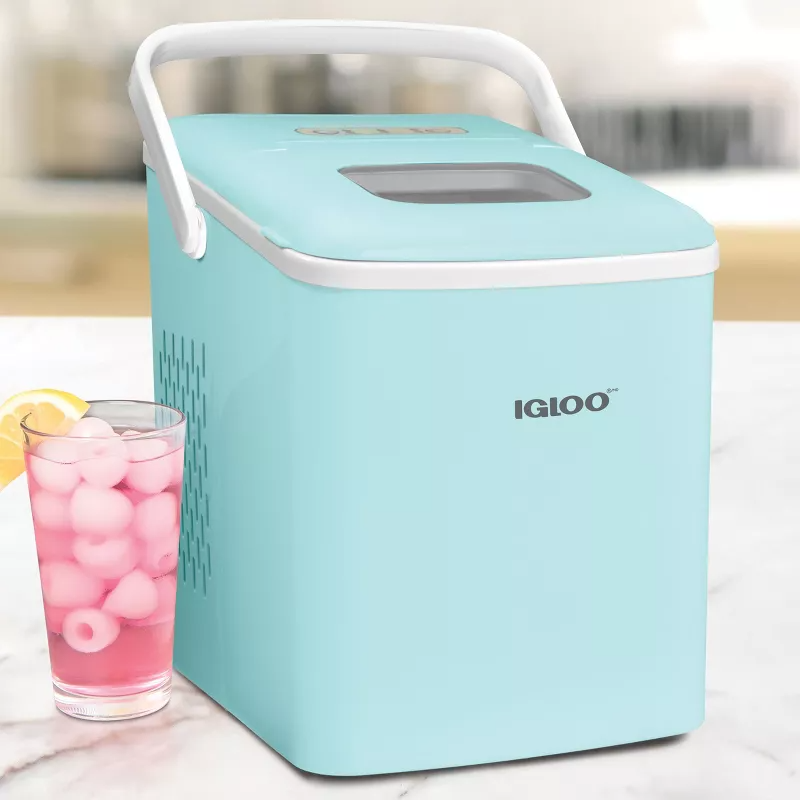 A turquoise portable Igloo cooler next to a glass of pink lemonade with ice cubes.