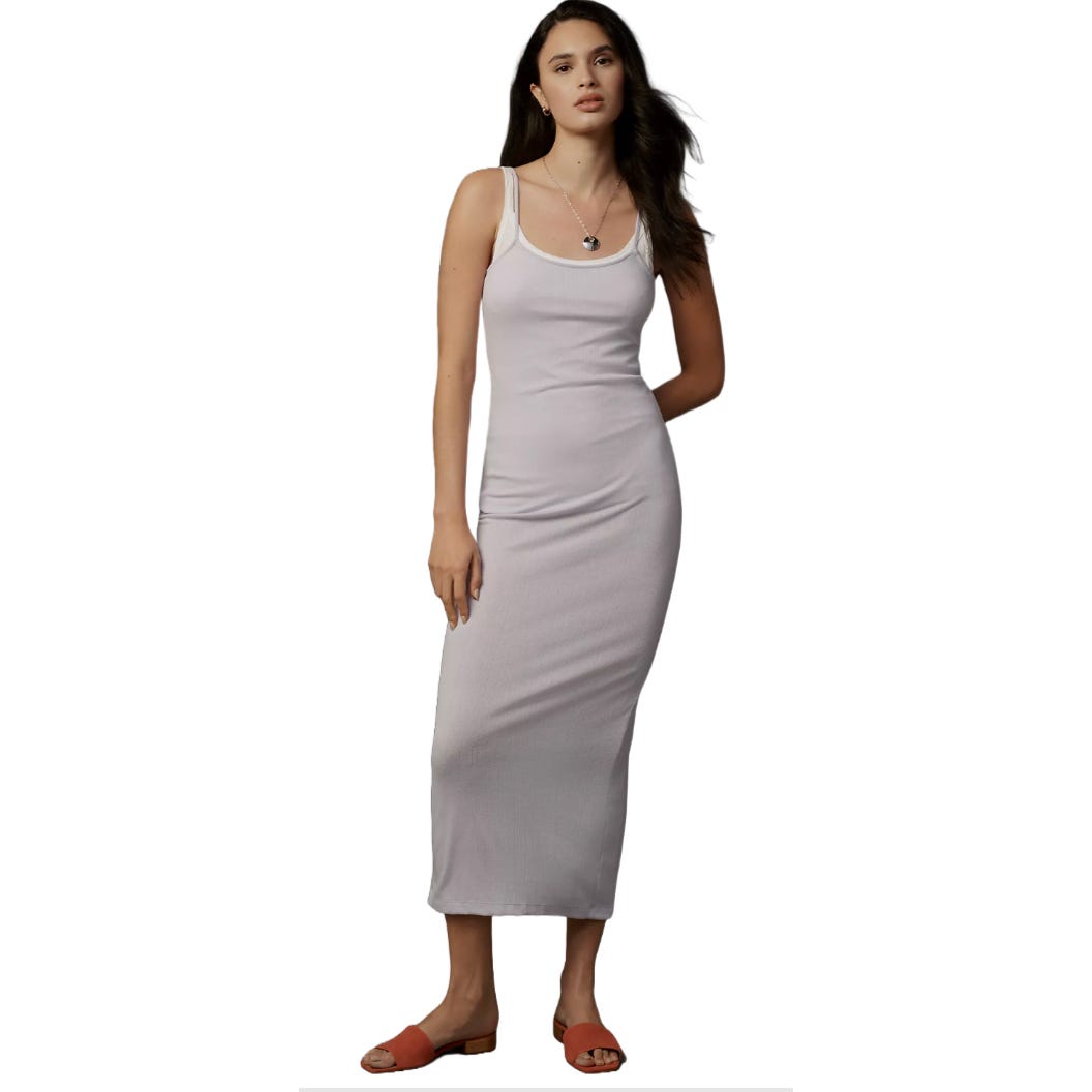 A woman wearing a sleeveless, fitted, ankle-length lilac dress with spaghetti straps and white trim, paired with coral flat sandals.