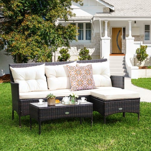 Outdoor wicker sectional sofa with white cushions and matching ottoman, accompanied by a tray with refreshments.