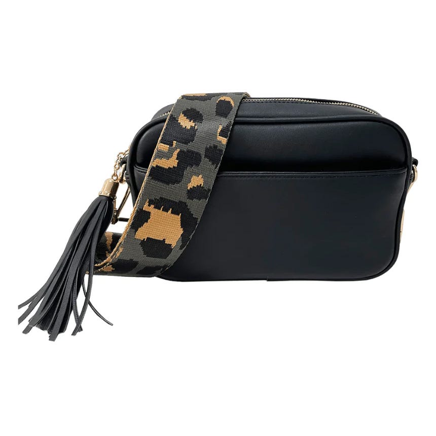 A black faux-leather crossbody bag with a leopard-print wide strap and a tassel accent. The bag features a simple, sleek design suitable for everyday use.