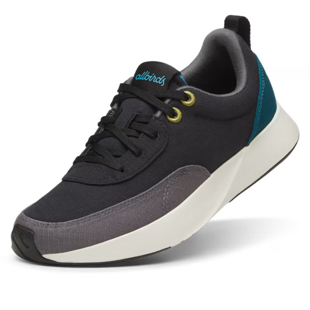 Allbirds Men's Courier Shoes feature a sleek design with a mix of dark fabric, contrasting teal heel detail, and light-colored sole. The shoe includes black laces and gold eyelets, combining style with a casual look.