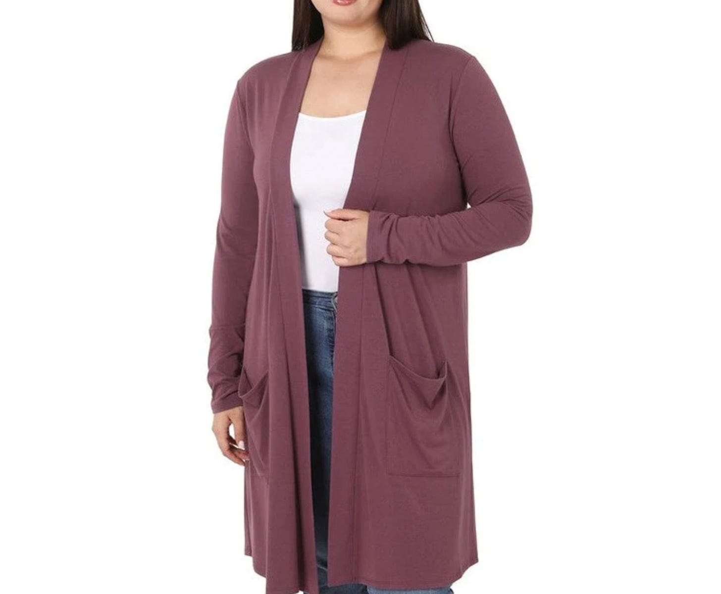 A woman in a long-sleeved, mauve cardigan with pockets, paired with a white top and blue jeans.
