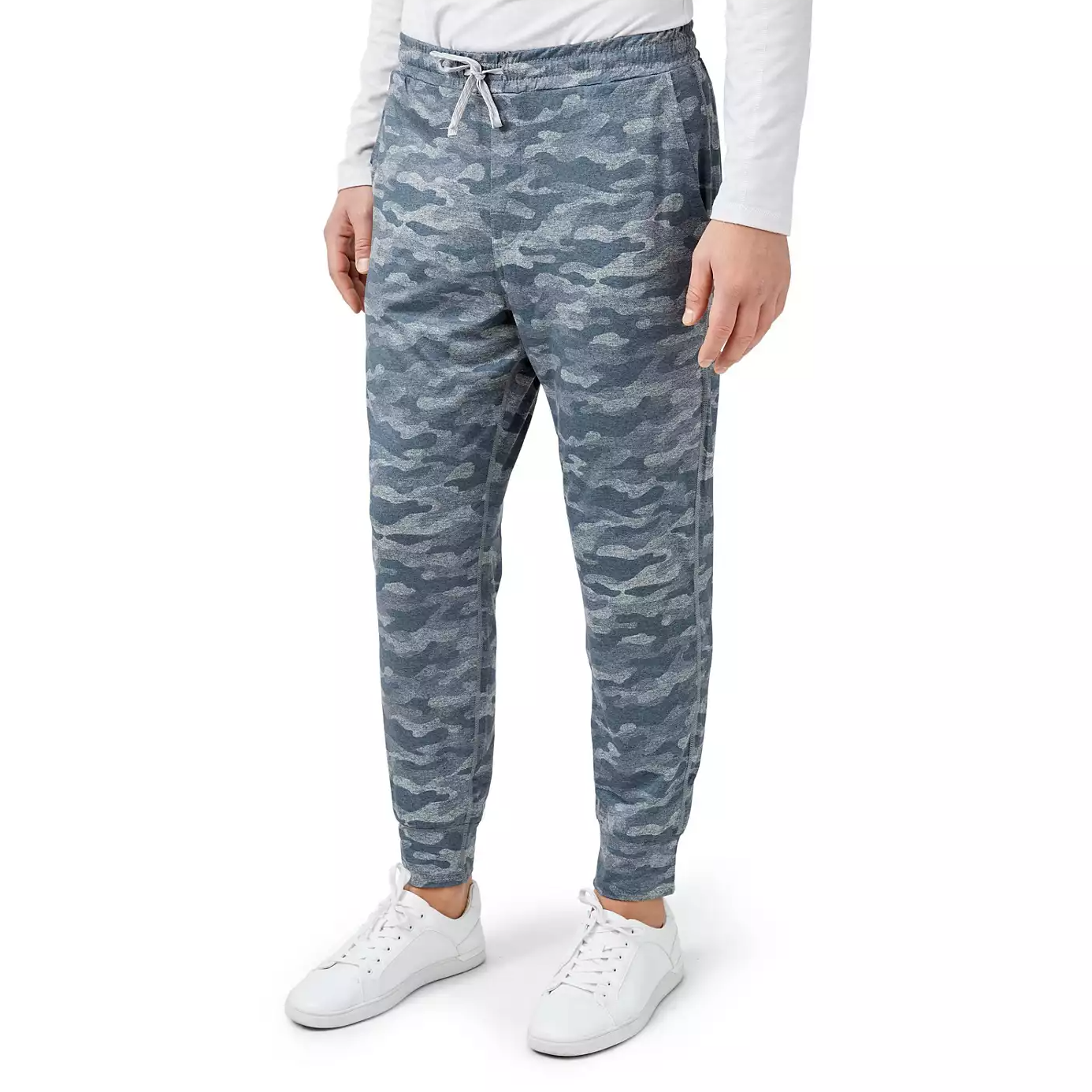 A person wearing camo print jogger pants and white sneakers.