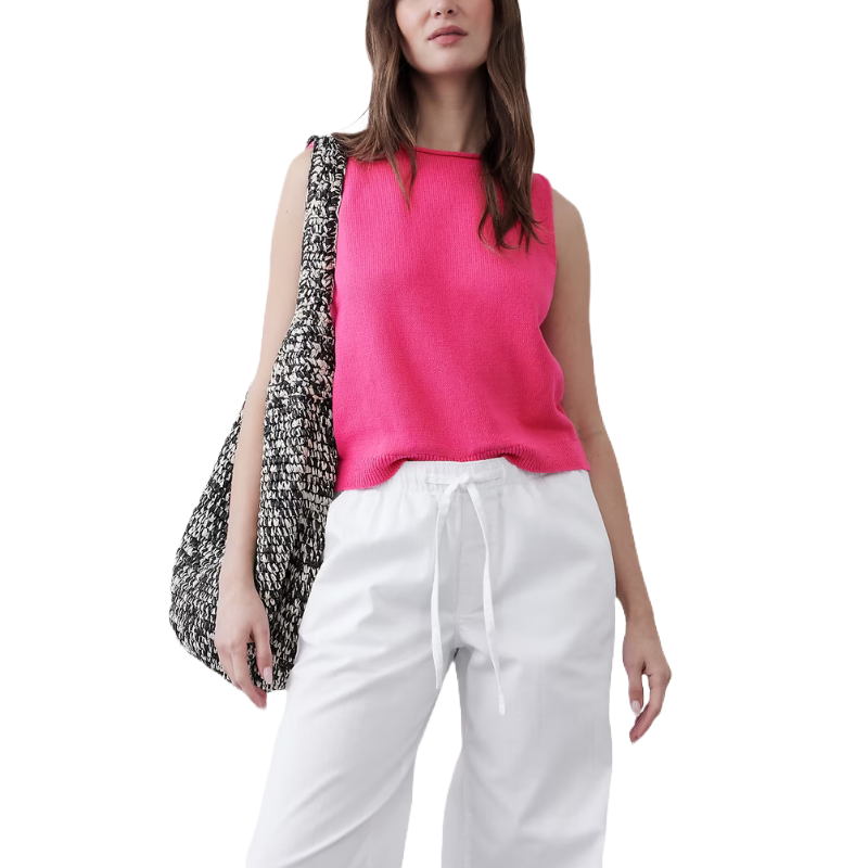 A sleeveless, bright pink cropped sweater with a boat neck design, paired with white drawstring pants and a black-and-white patterned tote bag.