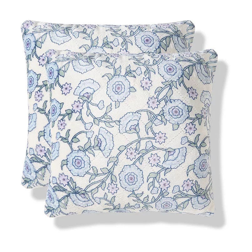 Two decorative pillows with a floral pattern featuring blue and purple flowers on a light background.