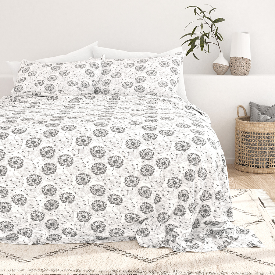 A floral-patterned bedspread with matching pillows in a bedroom setting, accompanied by decorative vases and a woven basket.