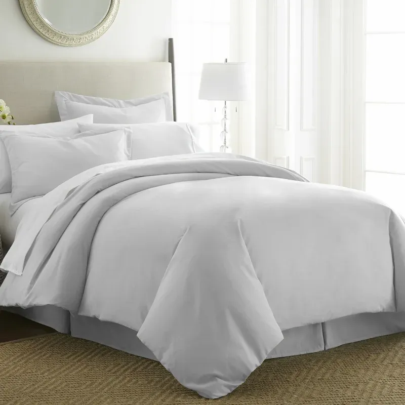 A neatly made bed with white bedding, including a duvet cover and pillows.