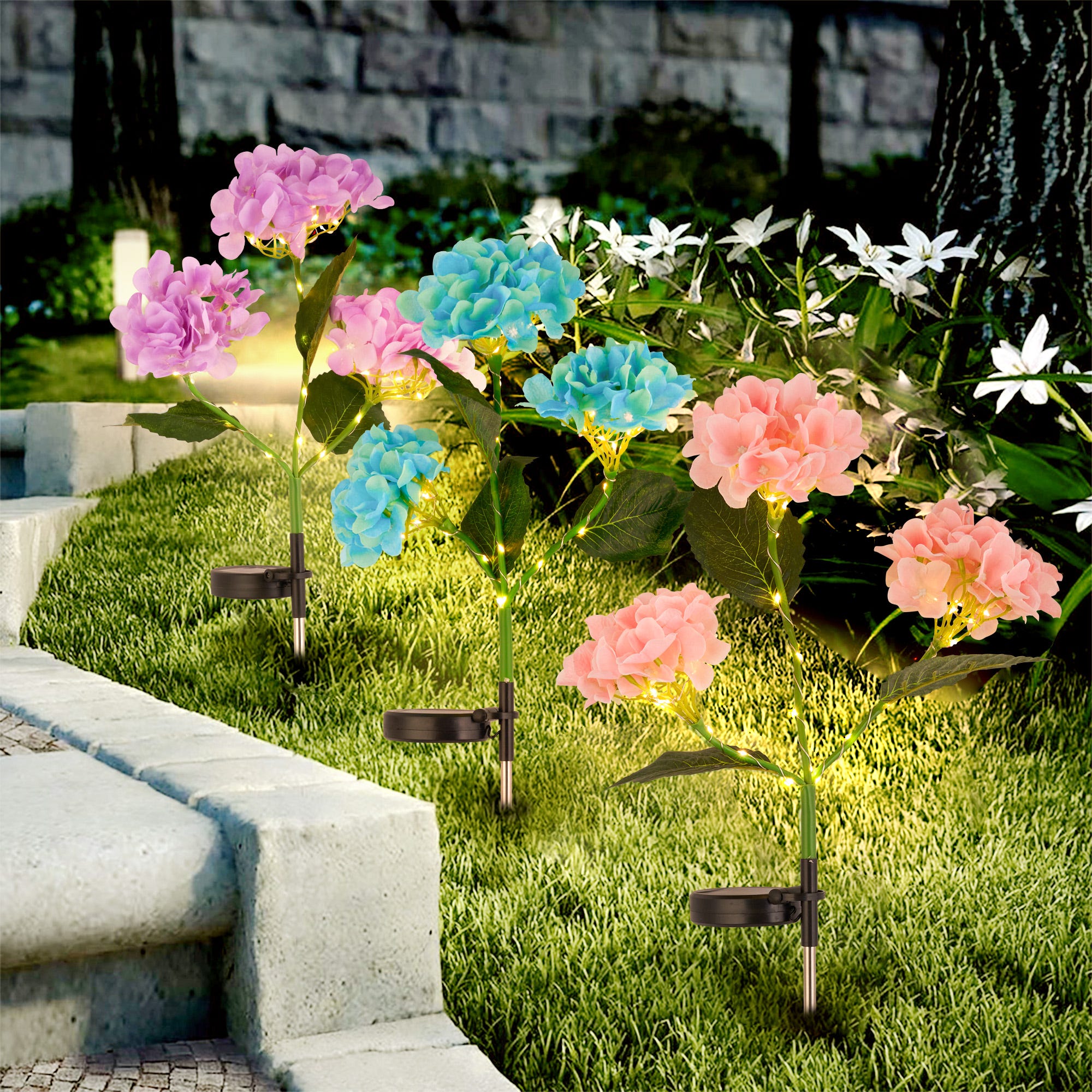 Two sets of solar-powered pathway lights designed to resemble hydrangea flowers, one pink and one blue, are displayed amid garden foliage. Each set features multi-colored blossoms on top of a stake.