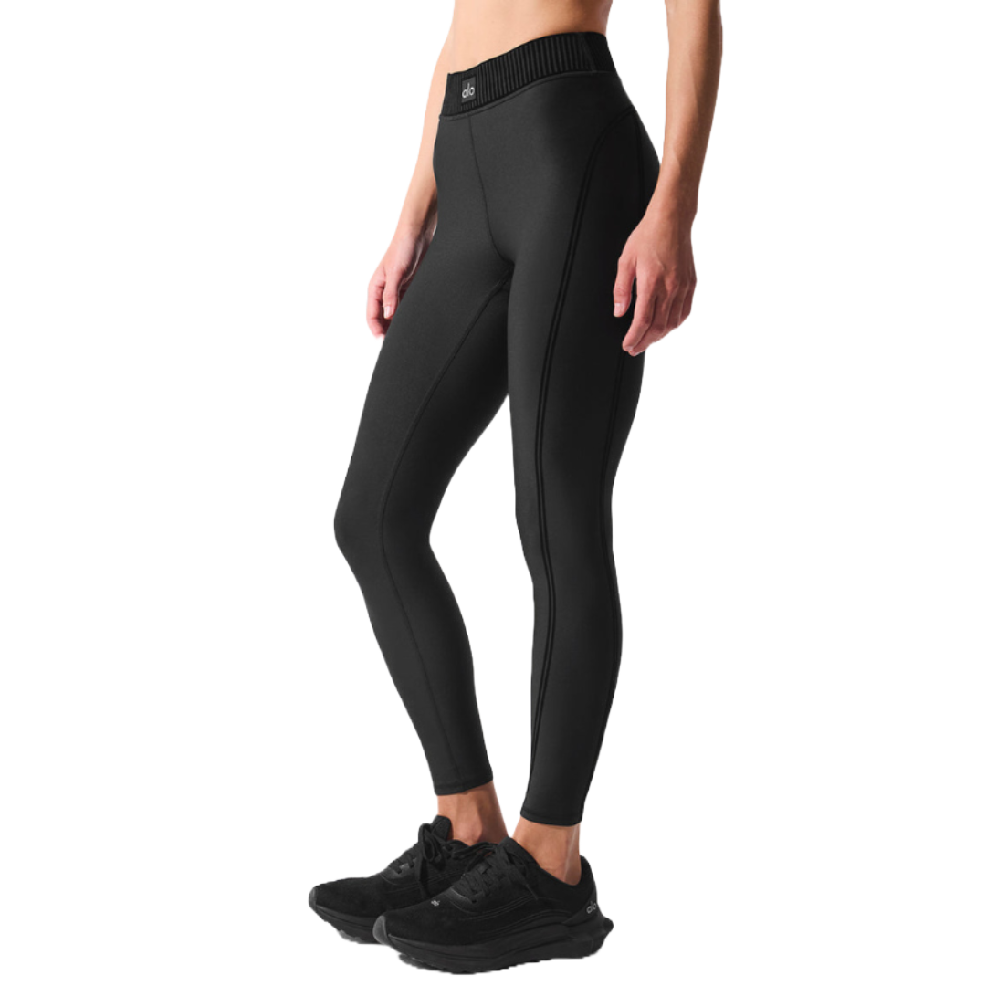 Black high-waist leggings with a ribbed waistband and smooth, form-fitting design, paired with black athletic sneakers.