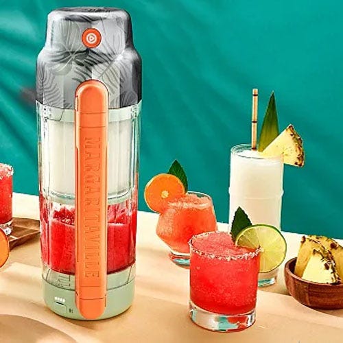 A portable blender alongside glasses of mixed drinks and tropical fruit garnishes.