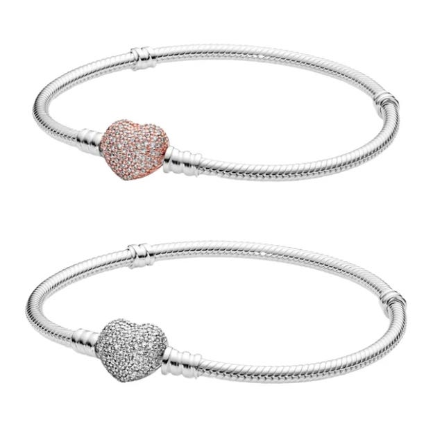 Two silver charm bracelets, each featuring a heart-shaped clasp encrusted with small stones. The top bracelet has a rose gold heart, while the bottom one has a silver heart.
