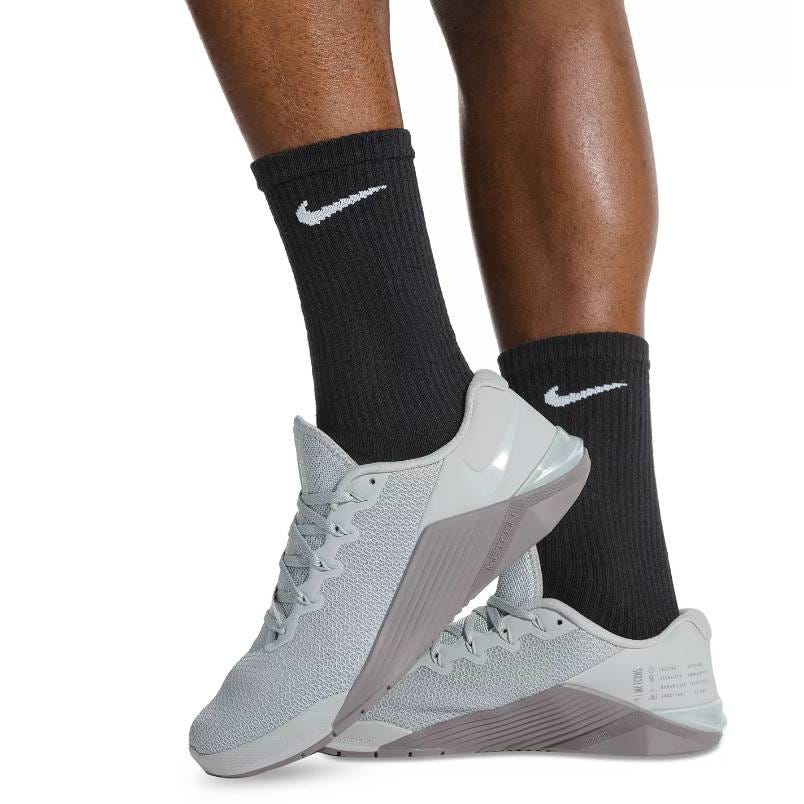 A pair of gray Nike sneakers and black crew socks with white logos.