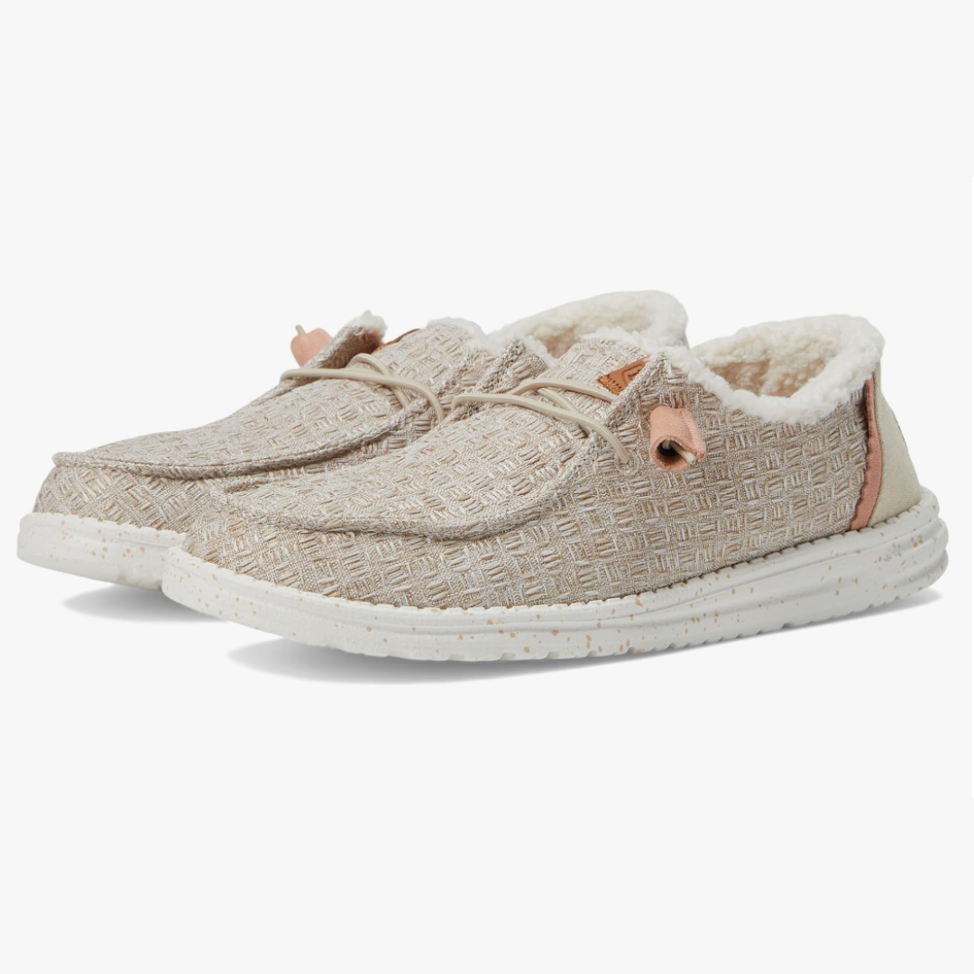 A pair of textured beige slip-on shoes with fleece lining and white soles.