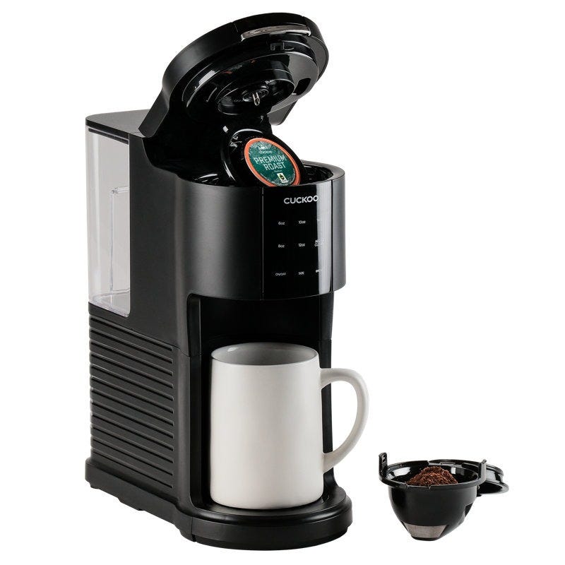 Black coffee maker with an open lid revealing a coffee pod, a white mug below, and a separate filter basket.