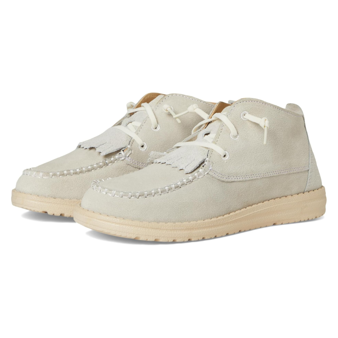 Light beige suede moccasin-style ankle boots with white stitching, fringe details, and rubber soles.