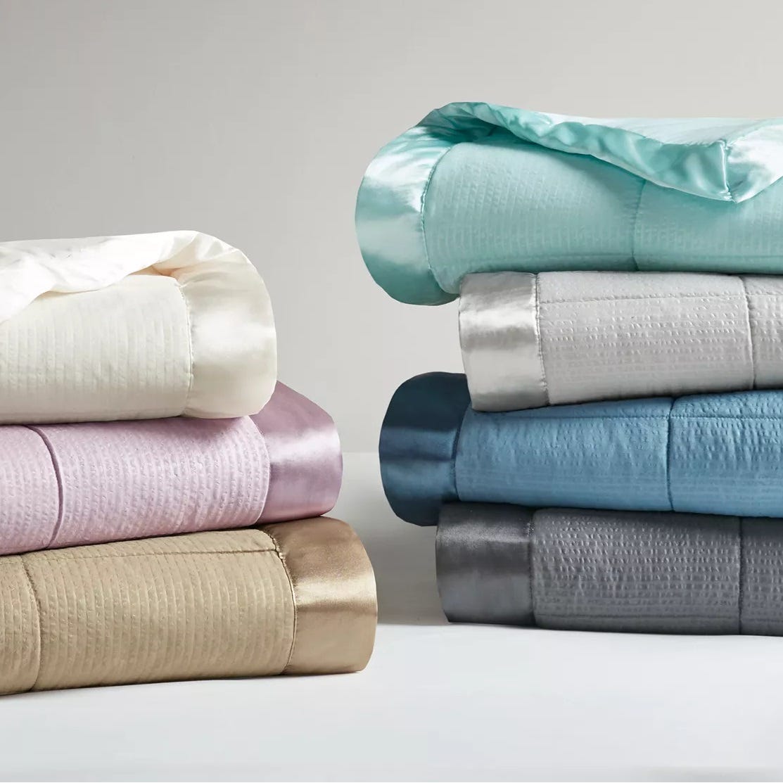 Stacks of folded bed sheets in various colors on a plain background.