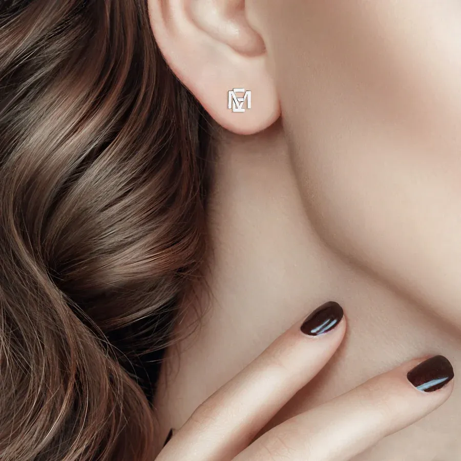 A person is wearing geometric-shaped stud earrings and showcasing dark polished nails.