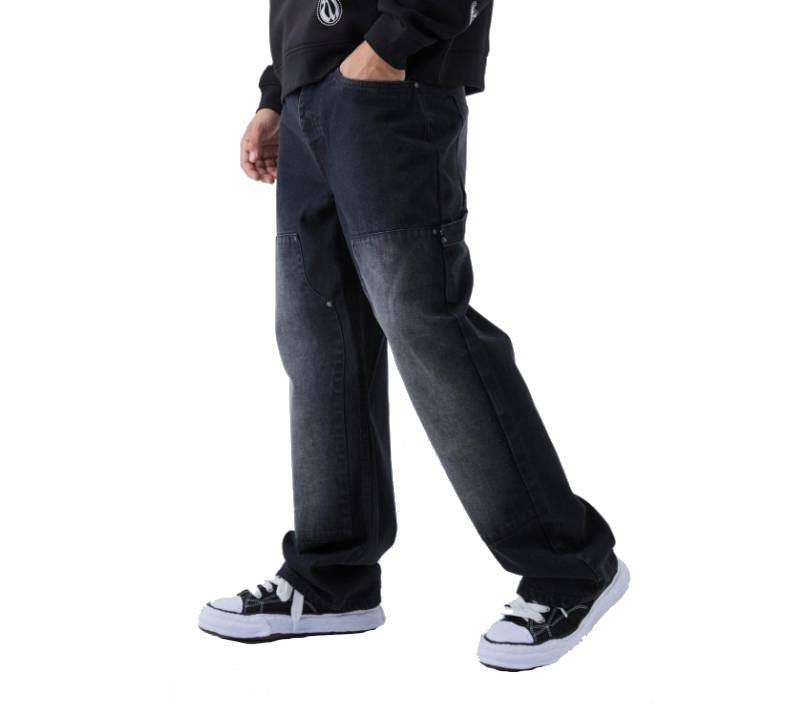 BooHooMan Carpenter Jeans are dark washed with a relaxed fit, featuring utility-style pockets and stitching. They are paired with a black hoodie and black-and-white sneakers.
