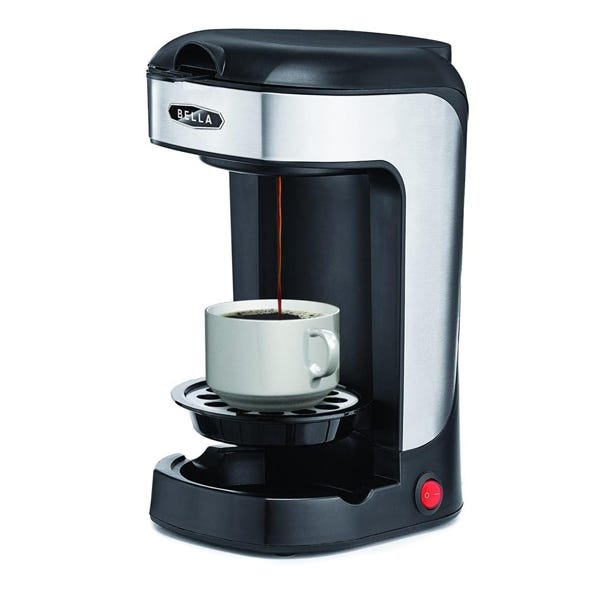 A single-serve coffee maker is brewing coffee into a white mug.