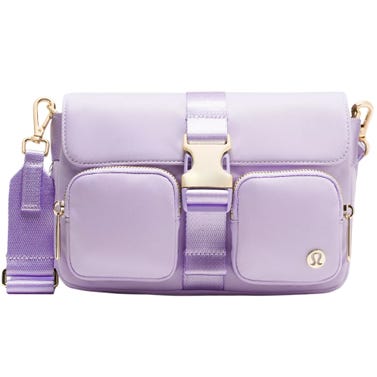 A lavender crossbody bag with front pockets, an adjustable strap, and gold-toned hardware.