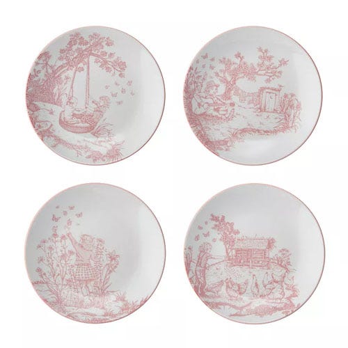 Set of four decorative plates featuring red toile-style designs with pastoral scenes, including children playing, a doghouse, and a person picking flowers.