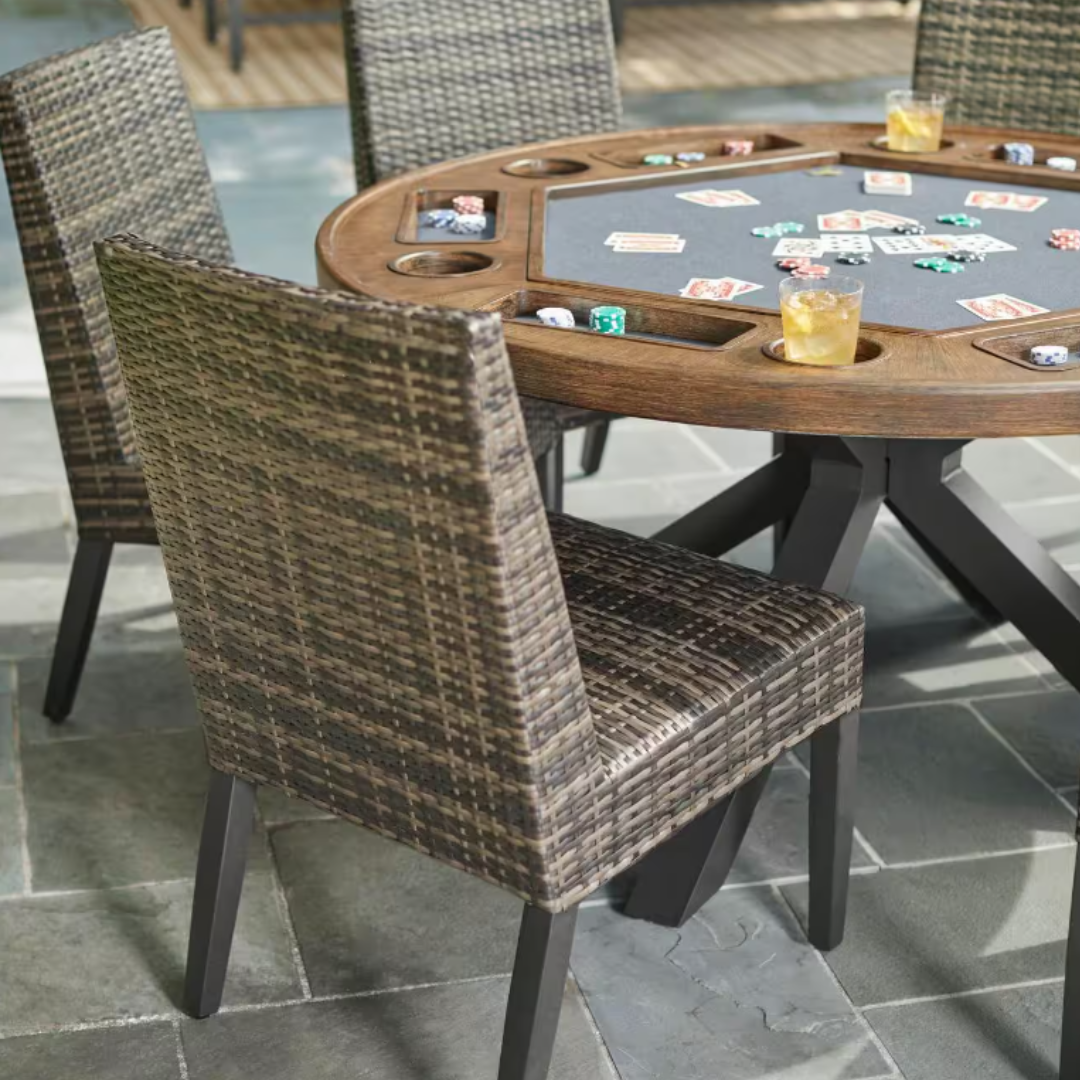 A round poker table with cup holders and a four-section chip tray, accompanied by woven rattan chairs.