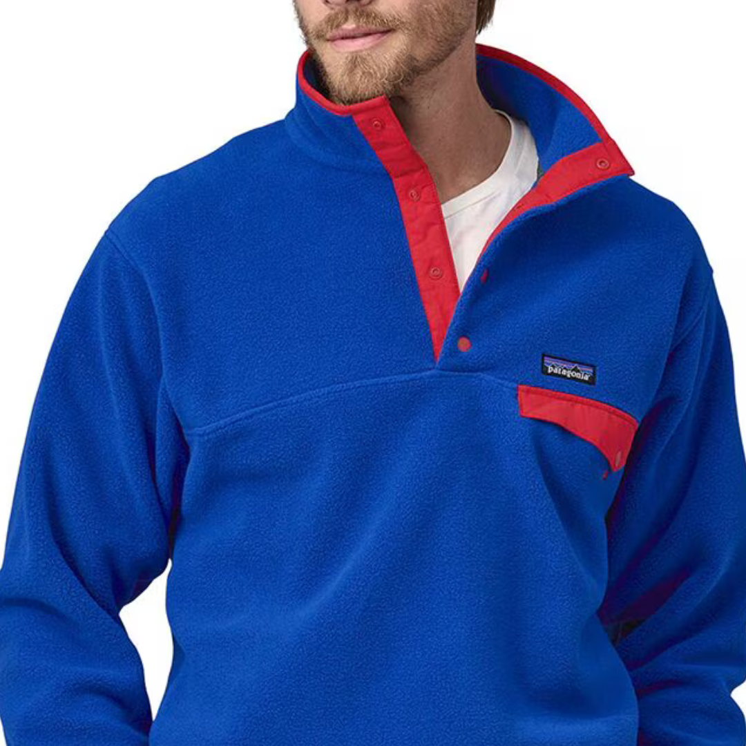 A man wearing a blue fleece pullover with red trim and a snap-button neckline.