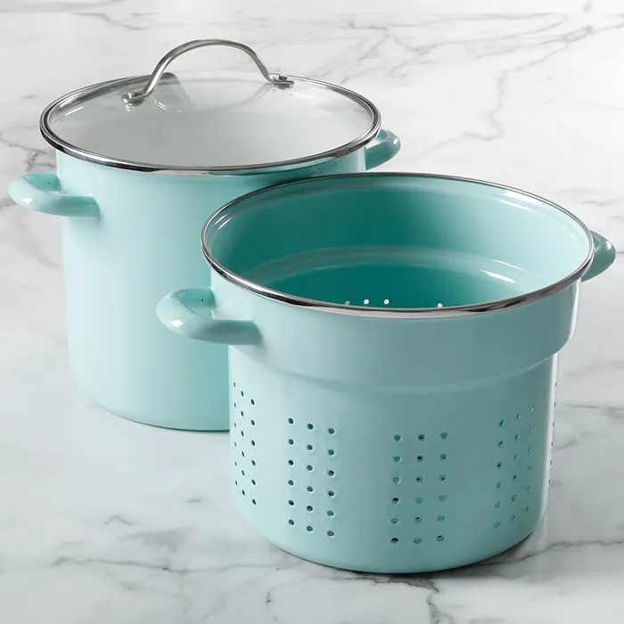 A teal pasta pot with a strainer insert and a glass lid on a marble surface.