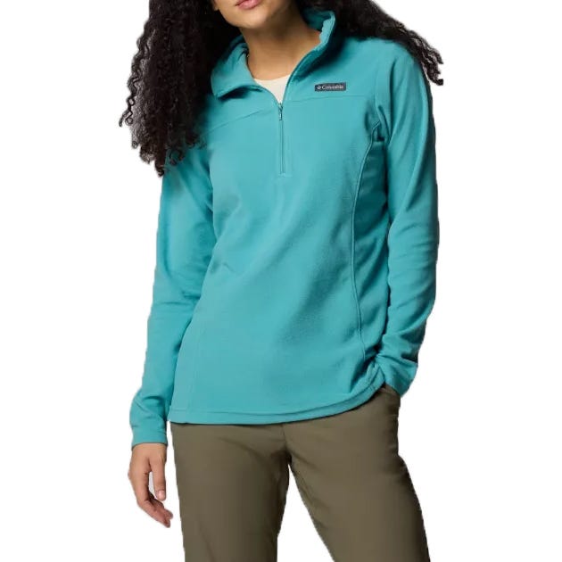 A woman is wearing a turquoise Columbia fleece pullover with a quarter-zip and long sleeves, paired with olive green pants.