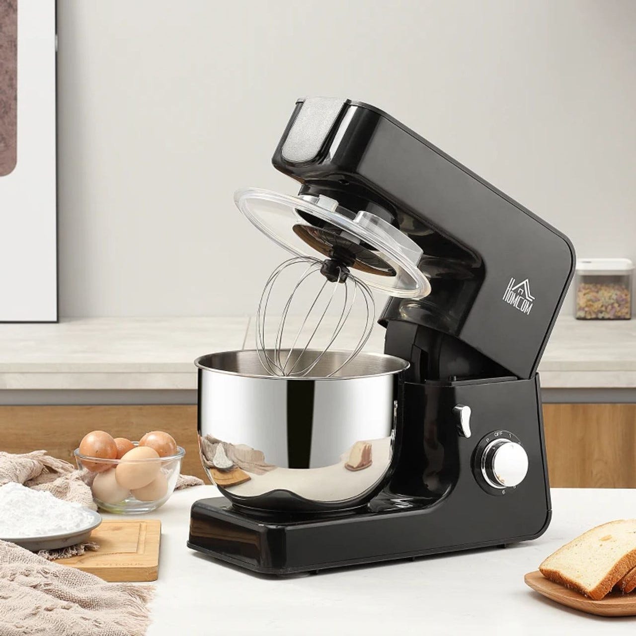 A black stand mixer with a stainless steel bowl and whisk attachment, set on a kitchen counter.