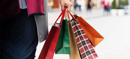 Hand holds holiday shopping bags on an autumn day.