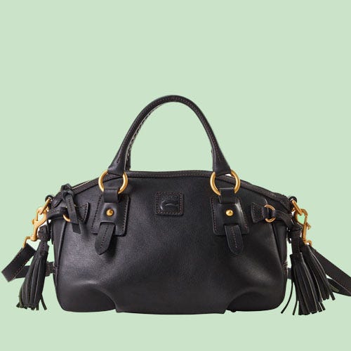 A black leather handbag with gold-tone accents and tassel details on a light green background.