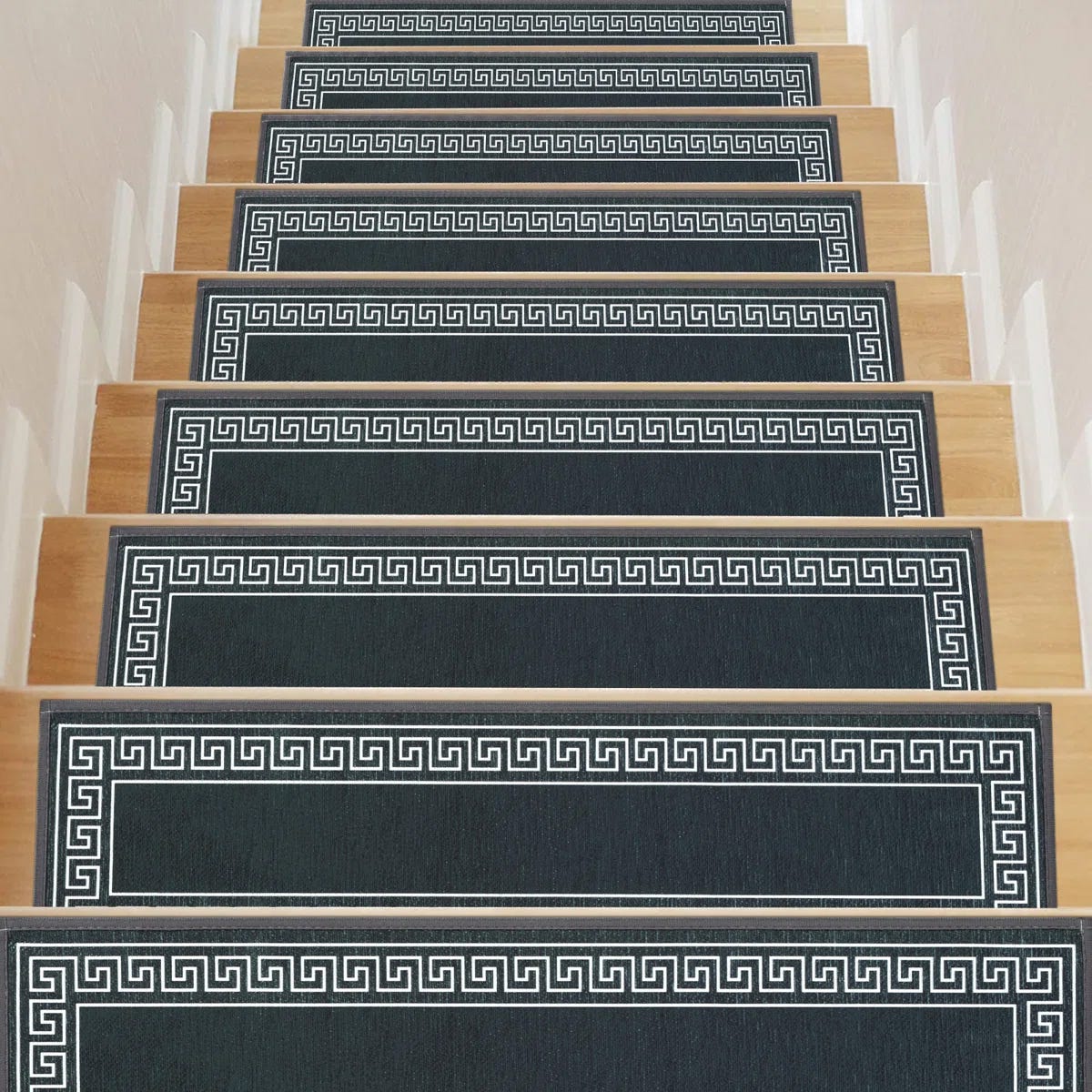 Stair treads with a Greek key pattern on dark fabric, set on light wooden steps.