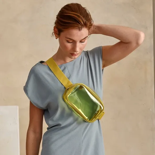A woman wearing a blue dress with a yellow strap translucent green crossbody bag.