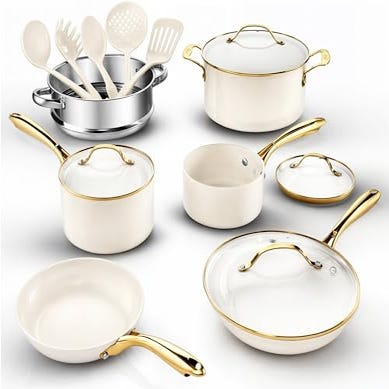 A cookware set featuring white pots and pans with glass lids and gold-colored handles, accompanied by gold and white utensils.