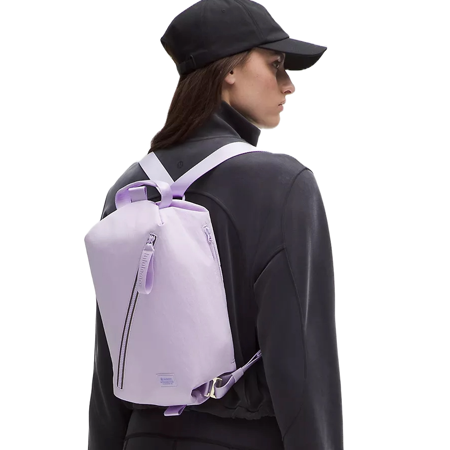 A person wearing a black cap and jacket carries a light purple backpack with white straps.
