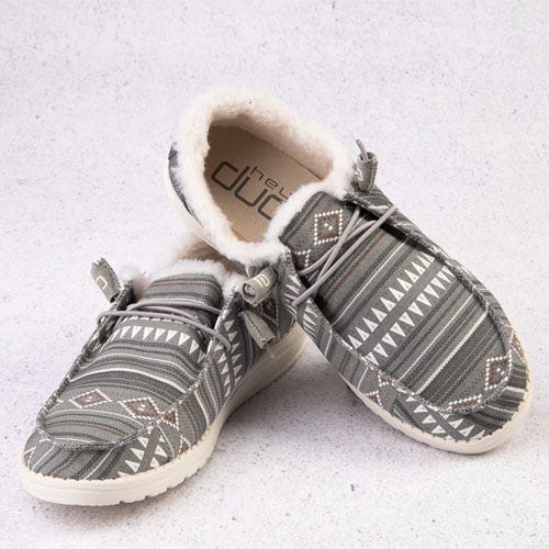 A pair of patterned grey slip-on shoes with fluffy white lining.