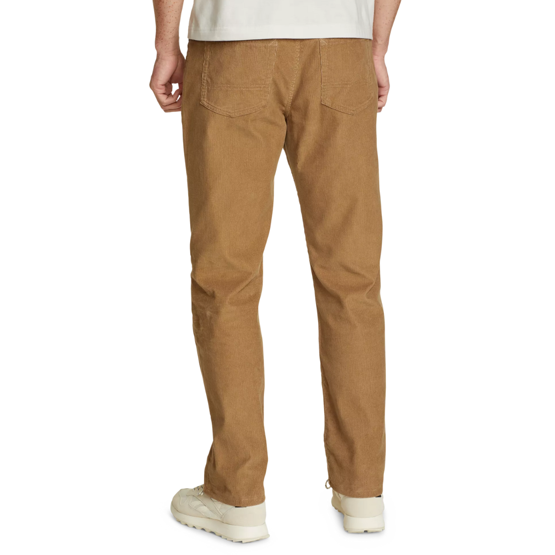 Tan corduroy pants with back pockets, worn by a person standing, paired with white sneakers.