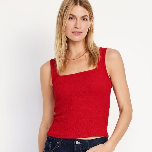 A woman is wearing a red sleeveless ribbed tank top.
