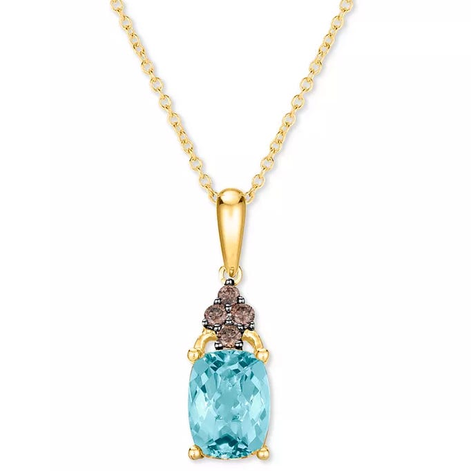 Gold necklace featuring a cushion-cut blue gemstone pendant adorned with small, dark stones in a floral design.