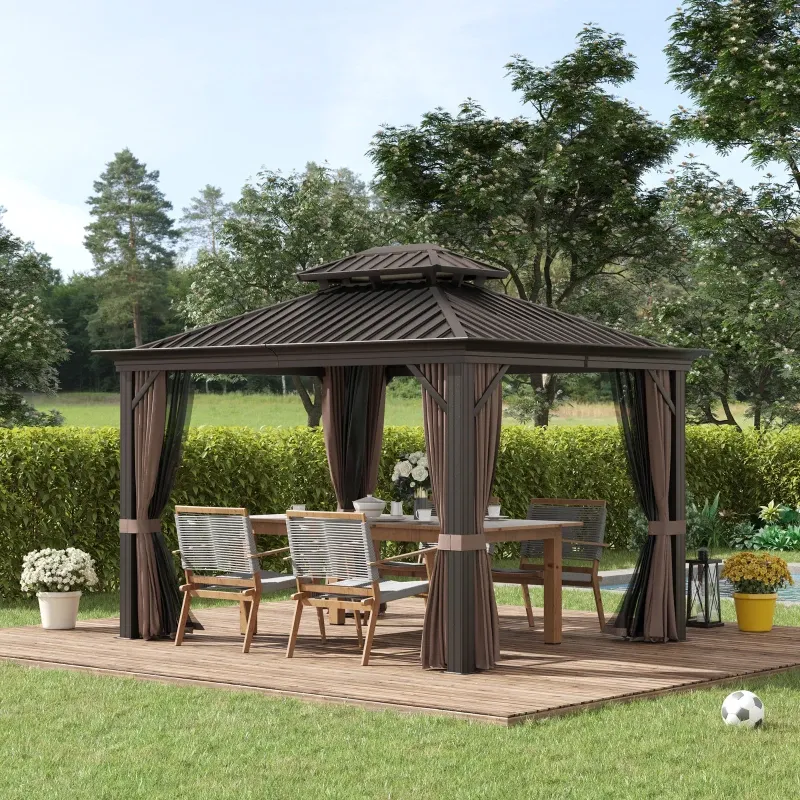 A brown hardtop gazebo with a vented roof design, featuring sheer curtains, housing a patio dining set with four chairs on a wooden deck amidst a garden.