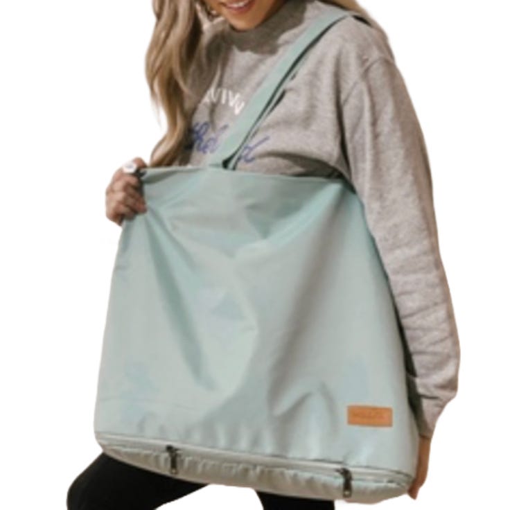 A person is carrying a large, mint green nylon tote with an adjustable shoulder strap and a bottom compartment possibly designed for shoes.
