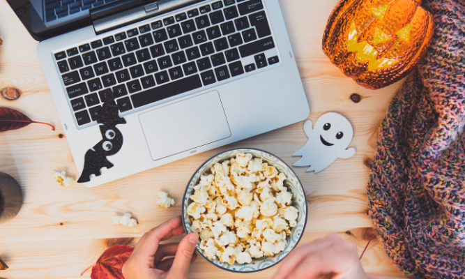 Halloween decorations and popcorn near laptop