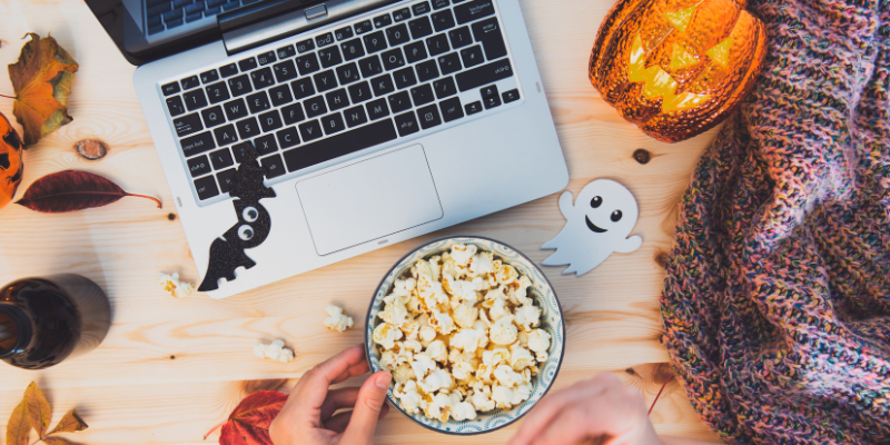 Halloween decorations and popcorn near laptop