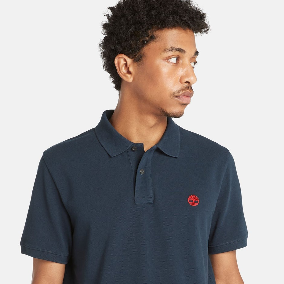 A man wearing a navy blue polo shirt with a small red logo on the chest.