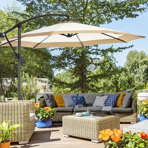 Large patio umbrella, wicker furniture set with cushions, and decorative outdoor plants.